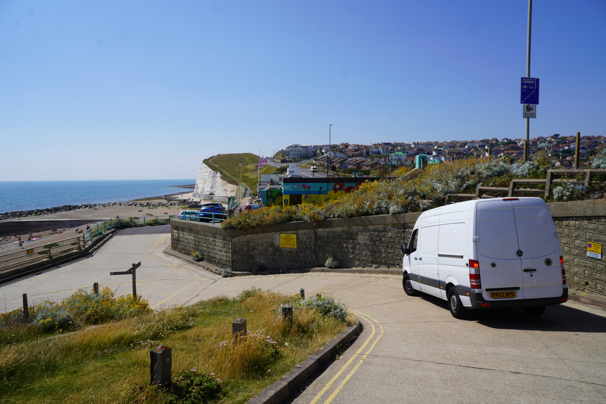ESV Removals Mercedes Sprinter on a coast road ramp east of Brighton, with white chalk cliffs, the beach and hillside houses behind