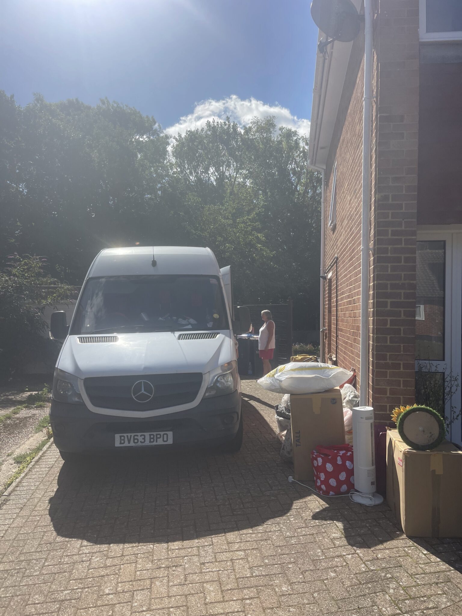 ESV Removals Mercedes Sprinter on a block paved drive beside a Burgess Hill house, with garden items and boxes lined up ready to load