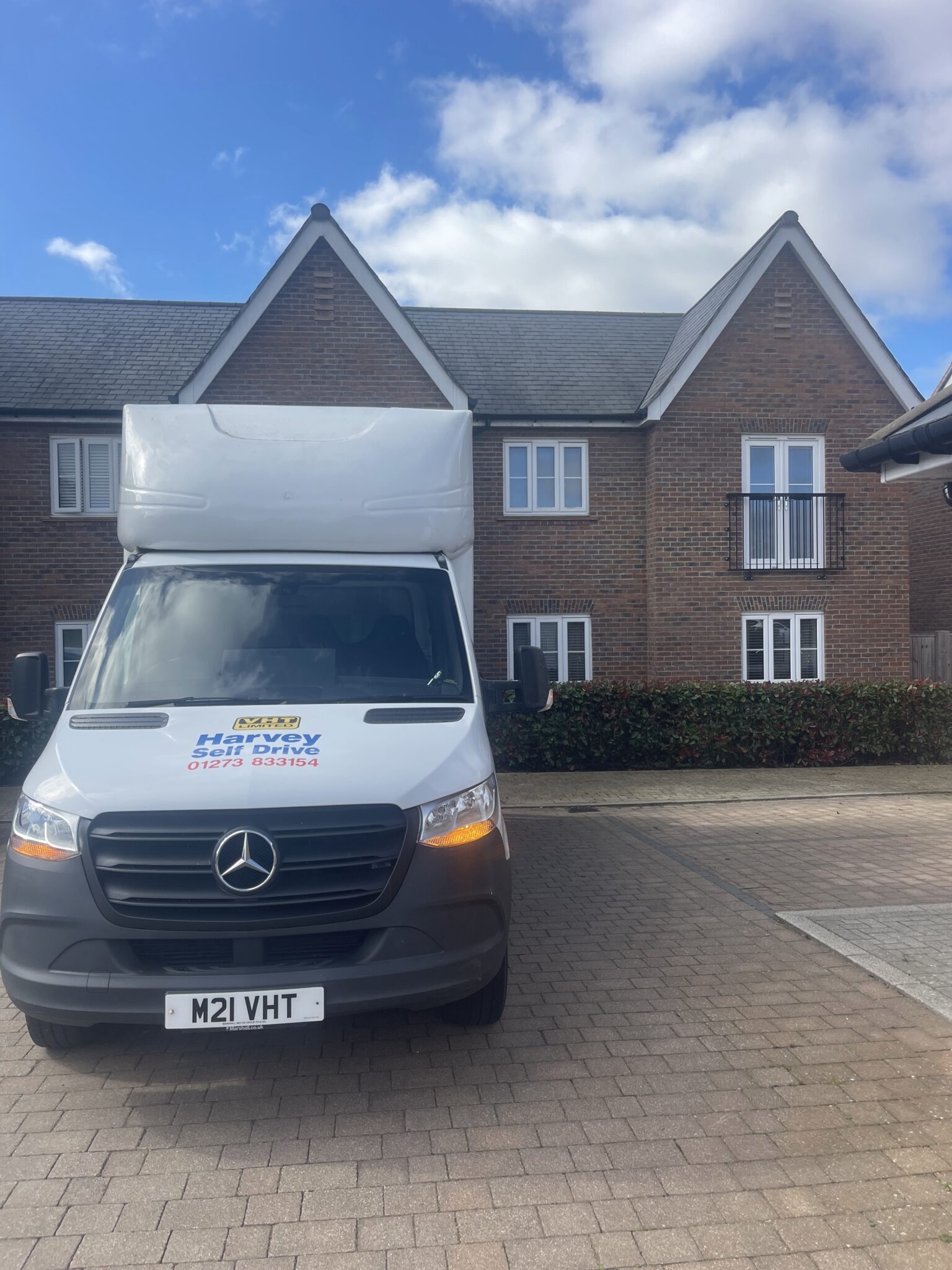 Front view of a white Luton van parked in a residential Burgess Hill street outside modern brick houses, showing clear access and easy loading space on moving day.