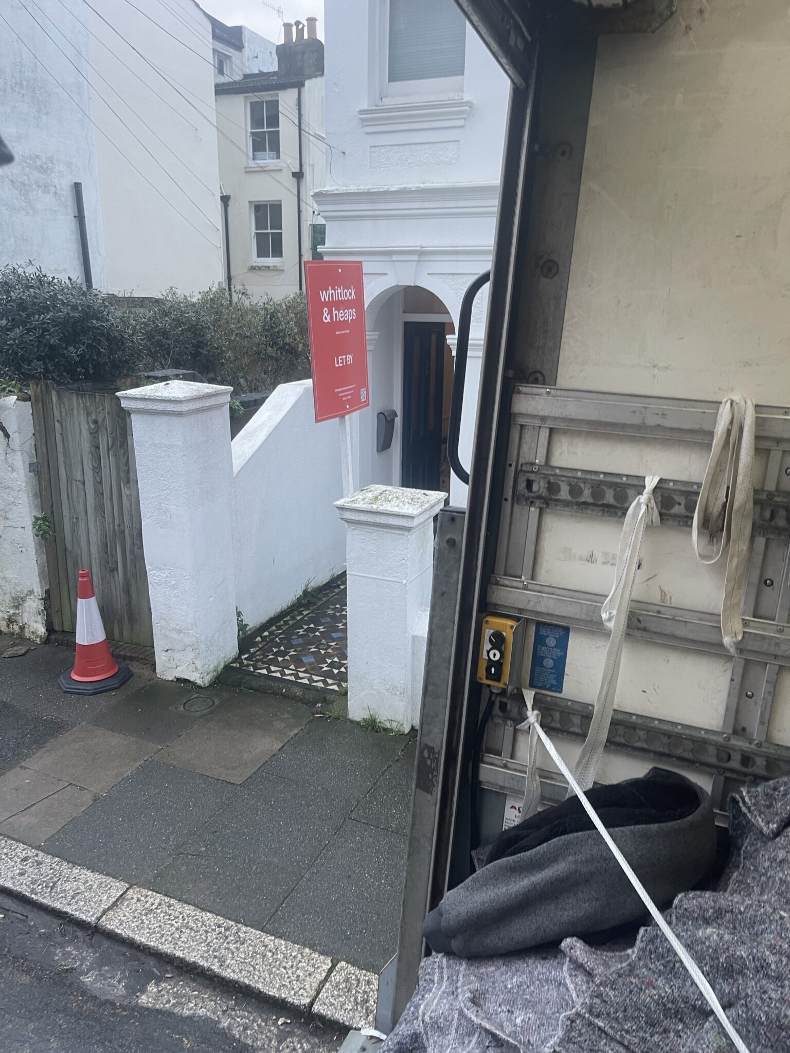 View from the back of a removals van to a Hove residential frontage, showing a tight pavement loading setup.