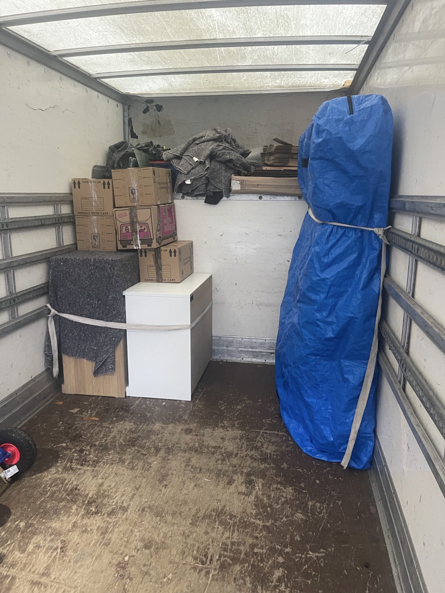 Secured Luton van load with moving boxes, padded furniture, and straps, packed for a Hove to Loughborough long distance move.