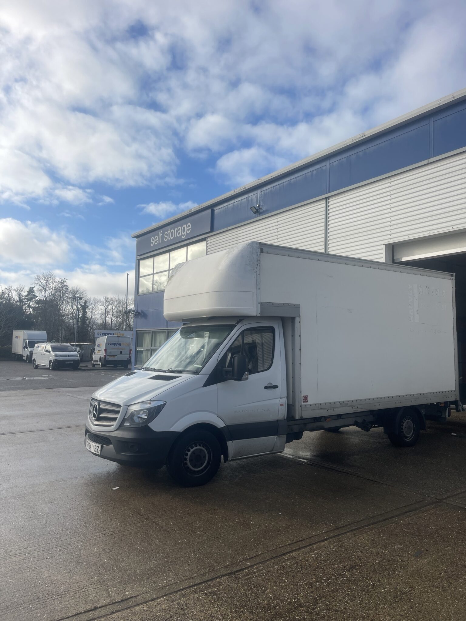 ESV Removals Mercedes-Benz Sprinter Luton van parked outside a self storage branch, shutter doors open behind it ready for the unload