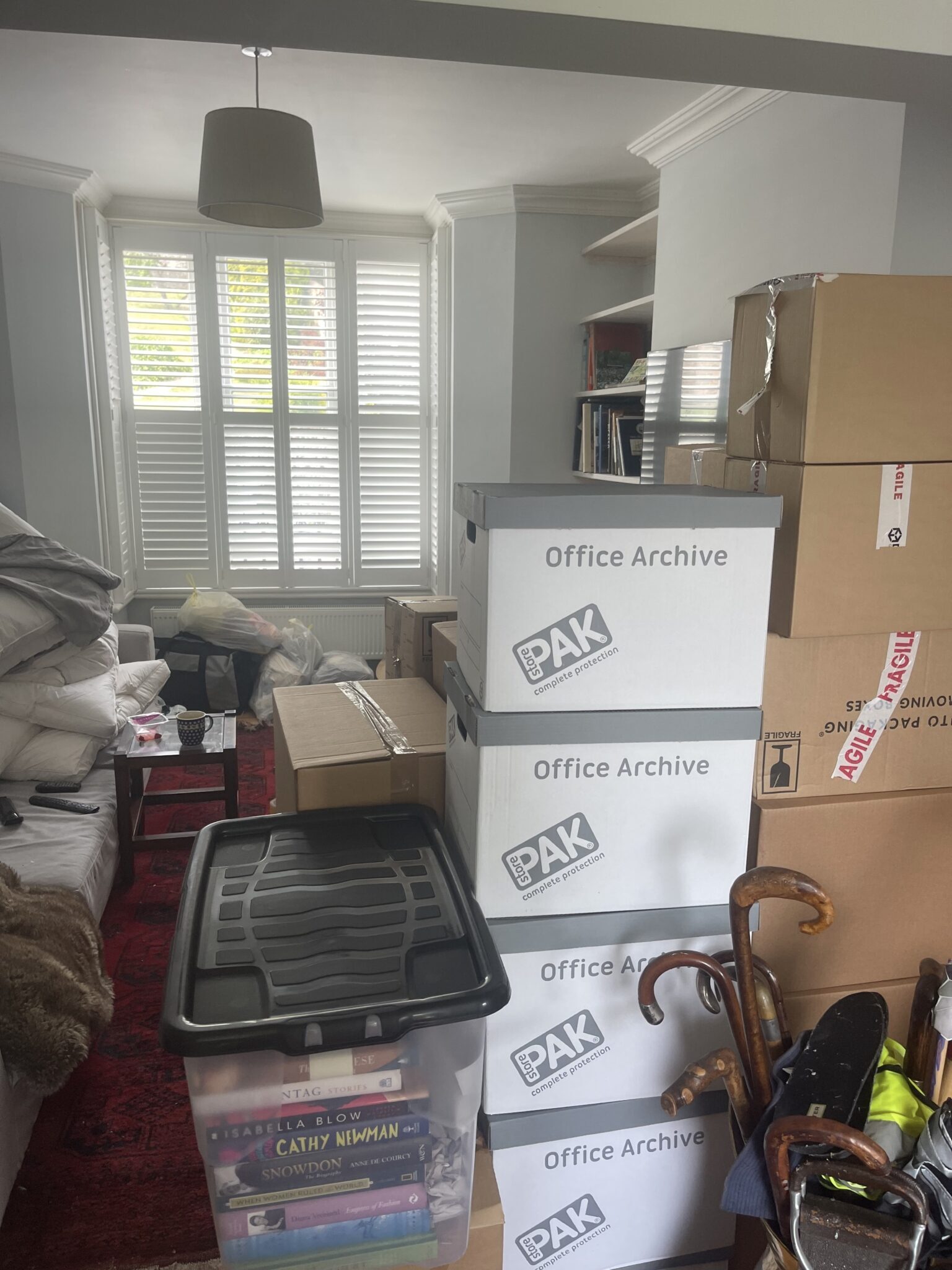 Living room in a Lewes home part-packed for moving, with labelled archive boxes and fragile-taped moving boxes stacked by a bay window