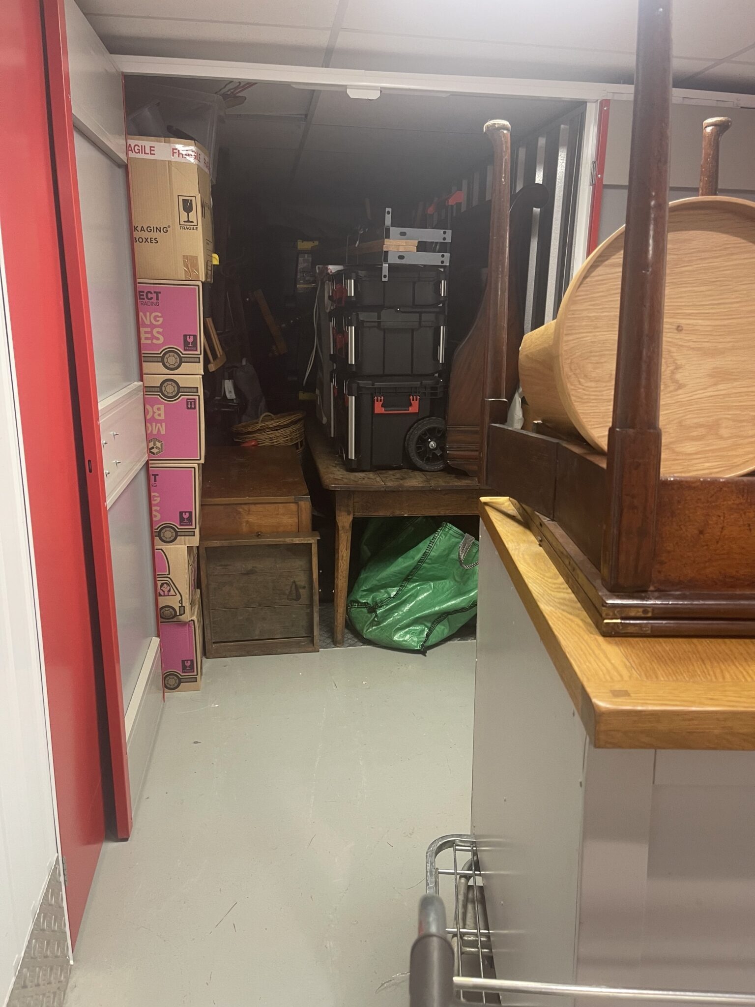 Interior of a Brighton self storage unit with boxes and wooden furniture loaded along the sides and a clear walkable lane left down the centre