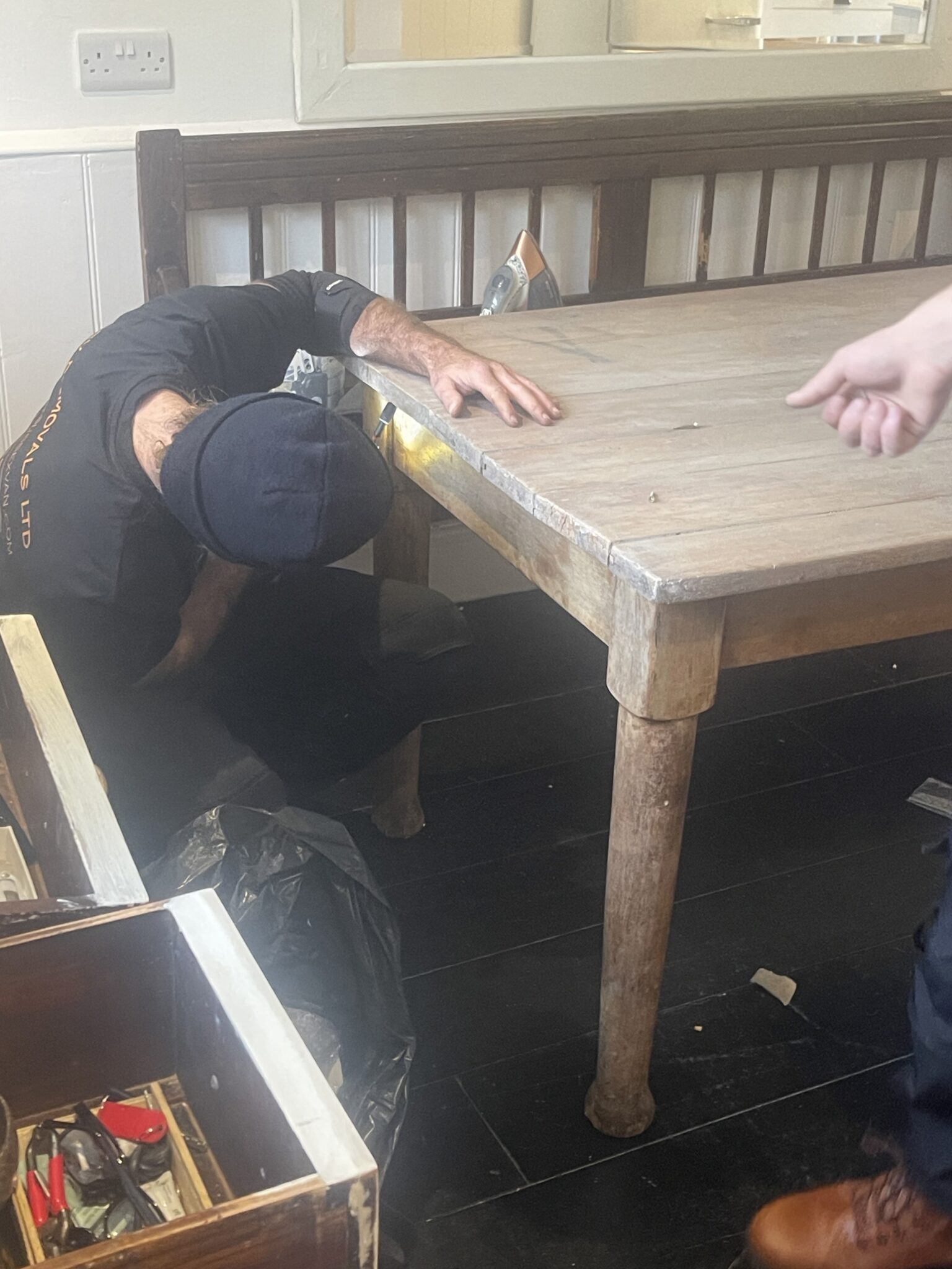 ESV Removals team member inspecting and tightening a wooden dining table with tools before a long distance house move from Sussex.