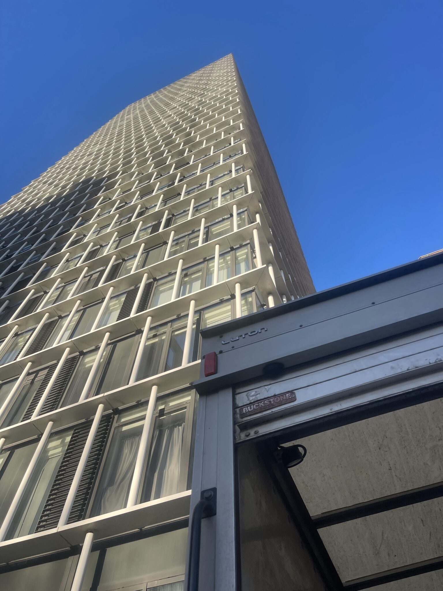 ESV Removals Luton van parked outside a modern London E15 high rise before a seventh floor flat move, showing the building height and access challenge.