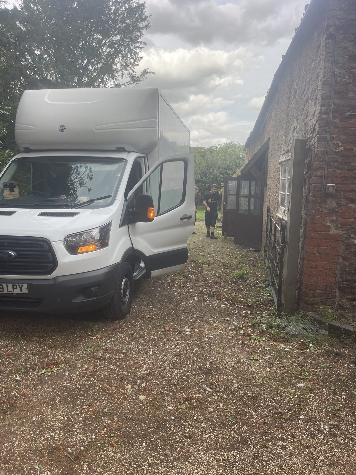 ESV Removals Luton van parked on a gravel drive beside an old brick cottage, with a crew member walking towards the door