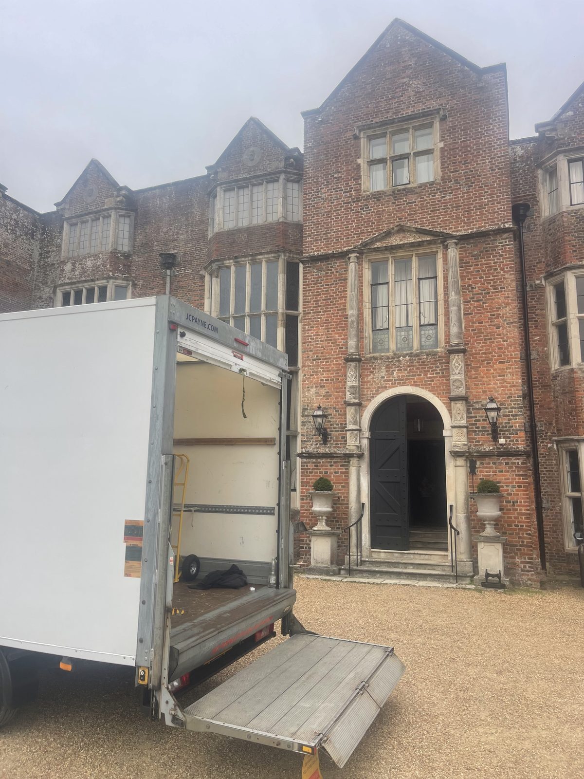 ESV Removals Luton van with its tail lift lowered on the gravel forecourt of Danny House, the Grade I listed Elizabethan mansion at Hurstpierpoint