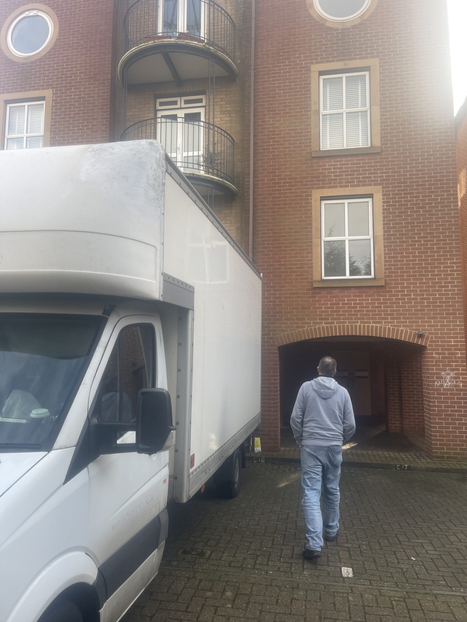 ESV Removals Luton van parked in a Southampton residential courtyard beside a brick apartment block, with a mover walking to the entrance for a first-floor flat delivery.