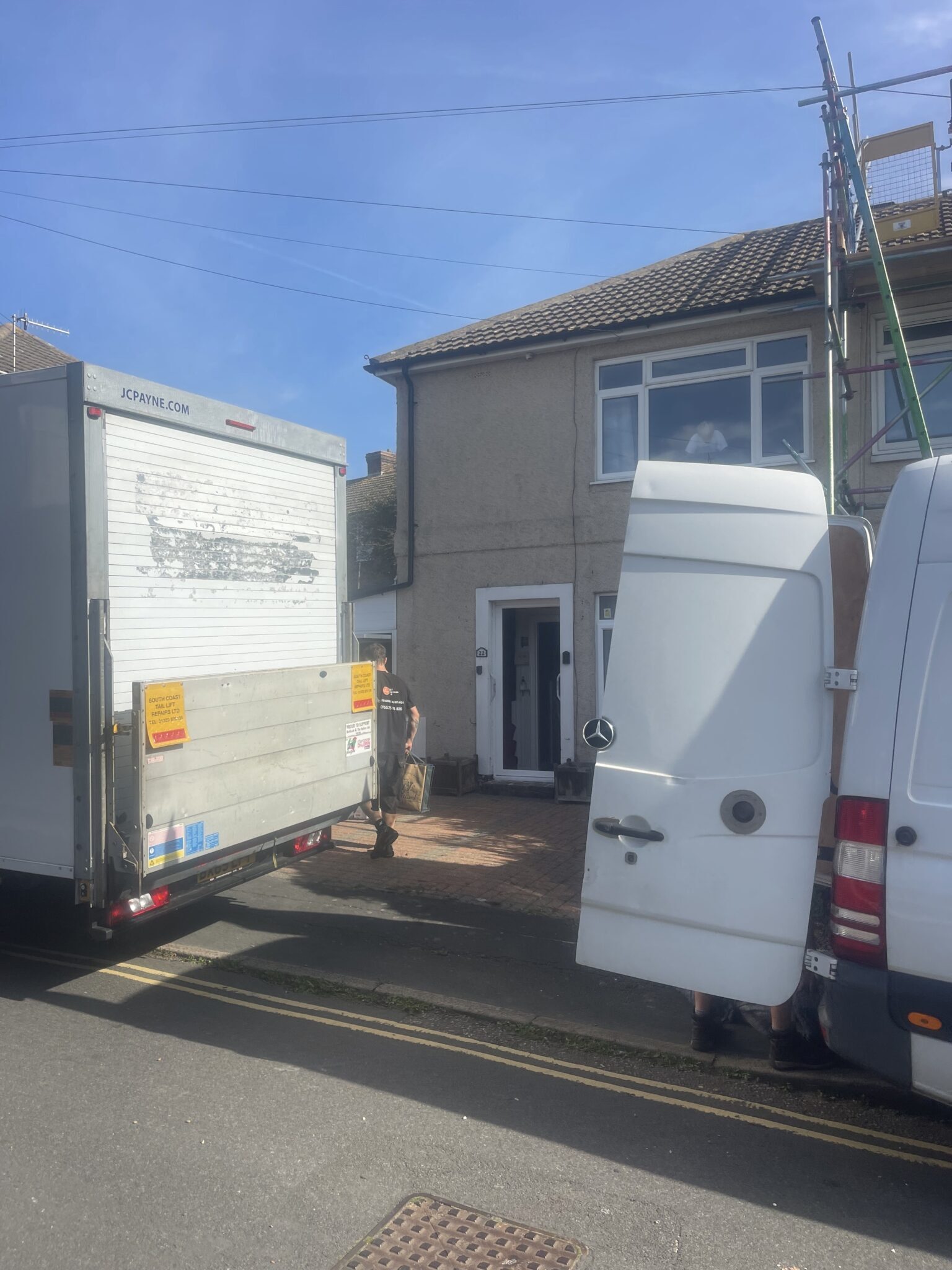ESV Removals Luton van with its tail lift down and a Sprinter with its rear doors open, both parked outside a semi detached house